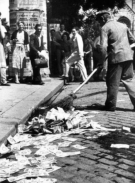 Дворник в Венгрии подметает обесценившиеся банкноты, 1946 г.